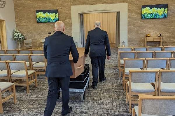 Funeral operatives taking coffin through chapel