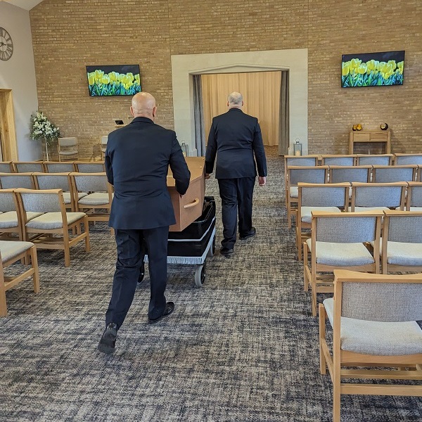 Funeral Operatives Carrying Coffin Through Crematorium Chapel