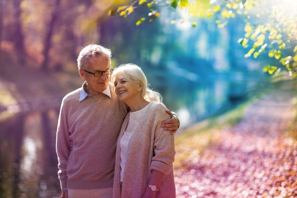 Smiling older couple walking by river in autumn