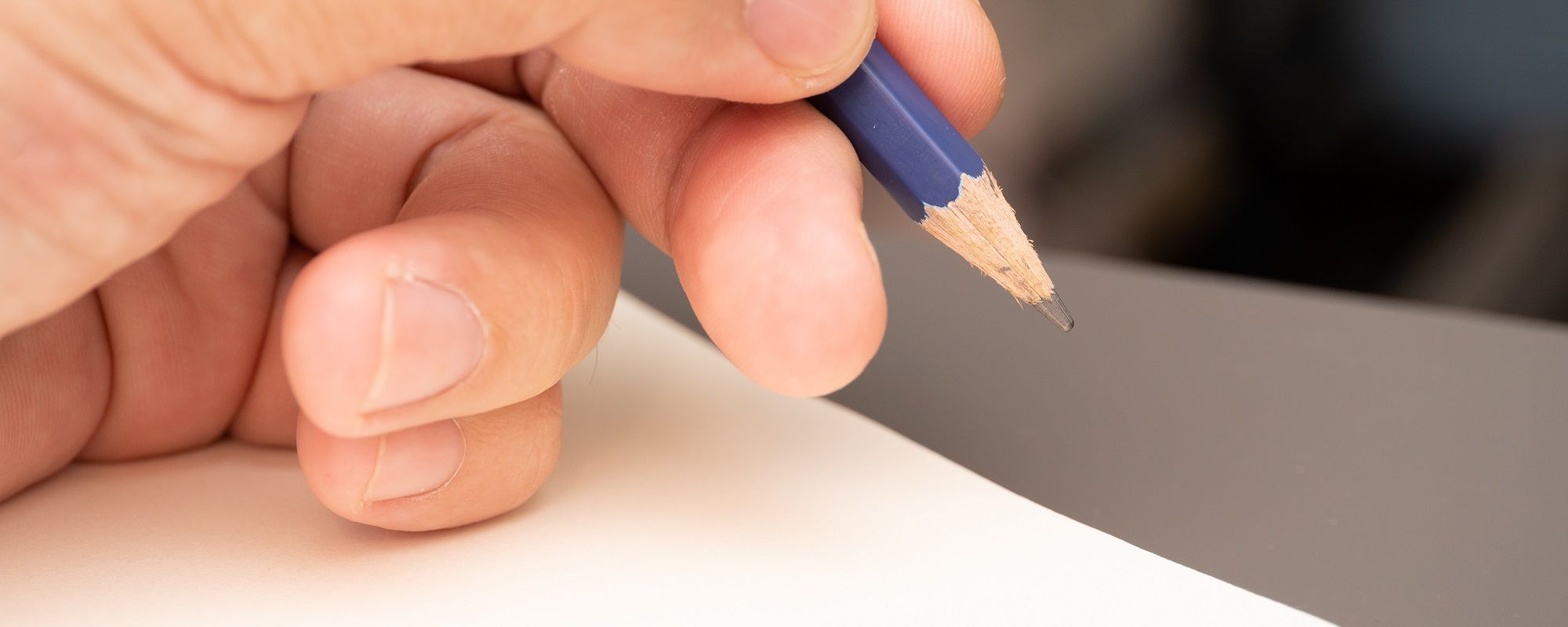 Hand Holding Pencil To Write Obituary
