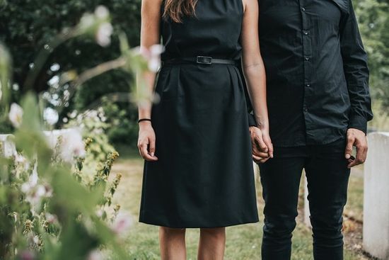 couple holding hands at a funeral dressed in black