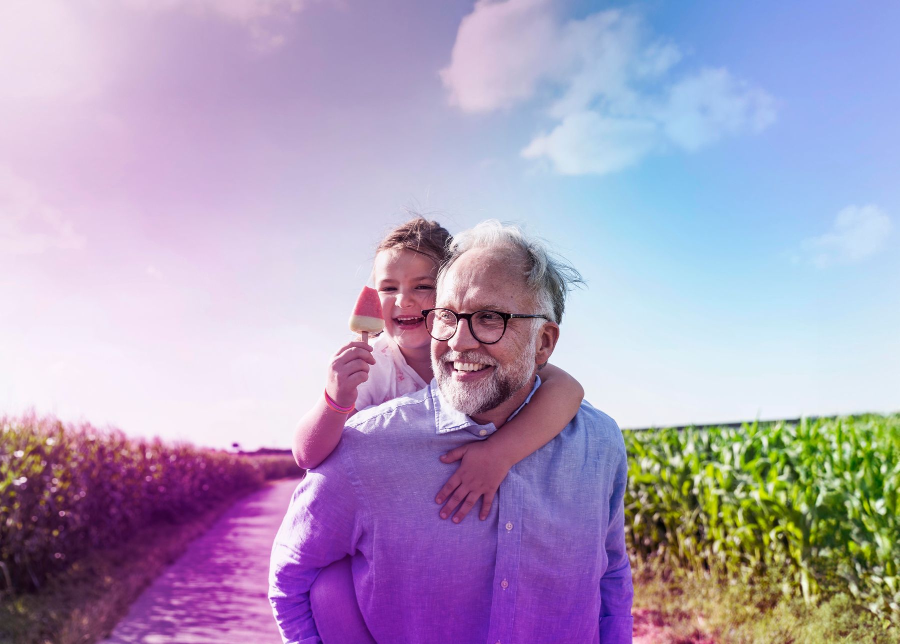 Grandfather and granddaughter walking in sunshine