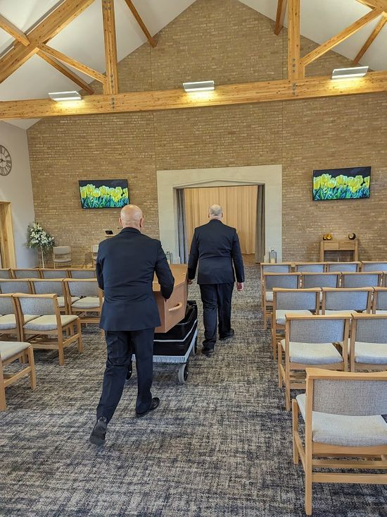 Funeral Operatives Transporting Coffin Through Chapel