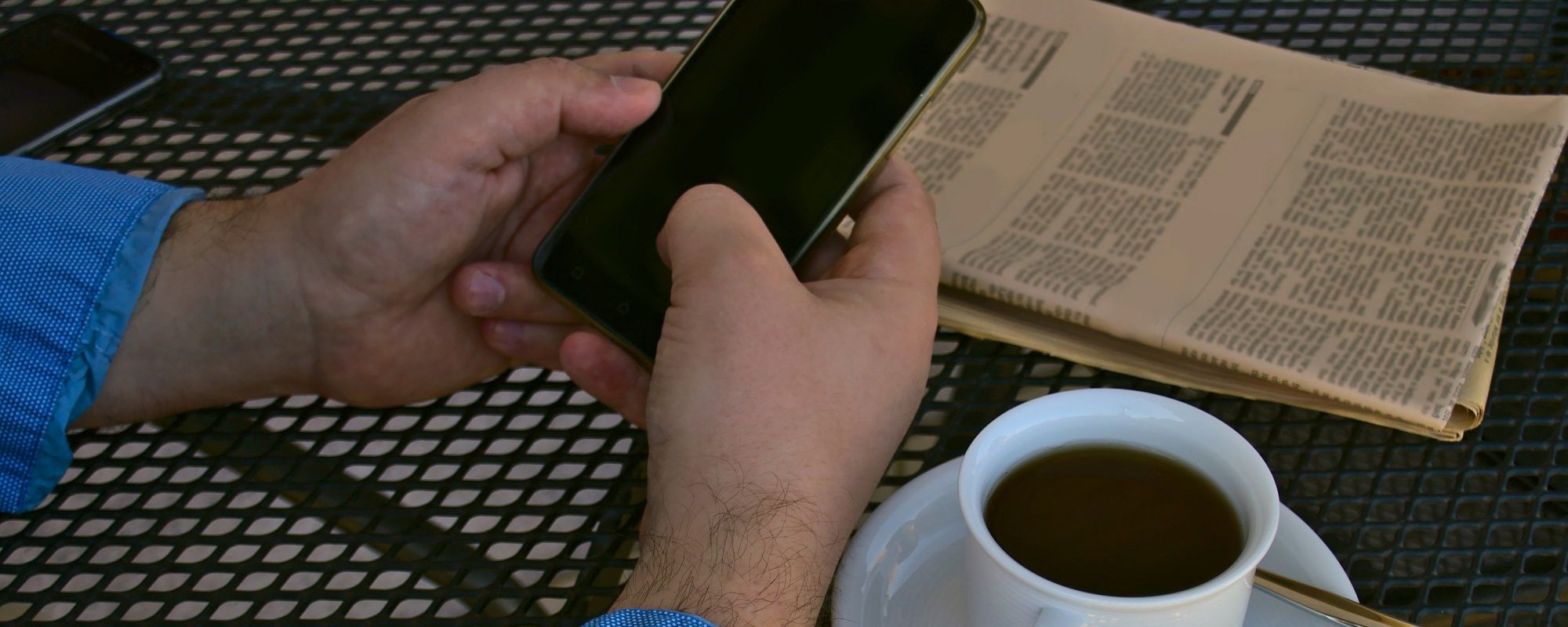 Man Reading News On His Phone And Newspaper
