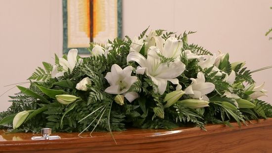 Wooden coffin with a bouquet of funeral flowers laid on top
