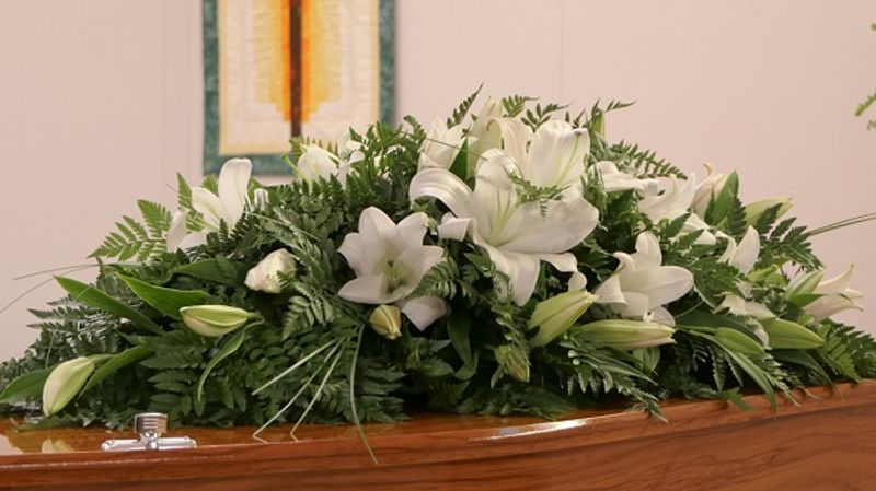 Wooden coffin with a bouquet of funeral flowers laid on top